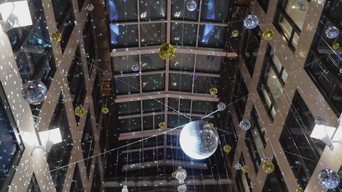 A mirrored disco ball suspended from the ceiling inside a high-rise building.