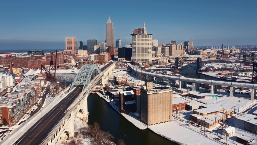 Drone push in shot of downtown Cleveland Ohio skyline on a sunny Winter afternoon with snow covering the landscape Royalty-Free Stock Footage #1085925371