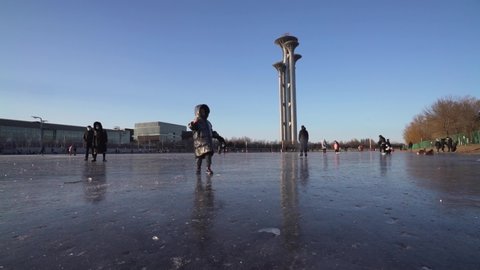 Beijing , China - 01 22 2022: People playing on frozen ice lake in front of Beijing 2022 Winter Olympic venue