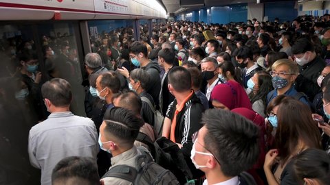 Hong Kong , Hong Kong Island , China - 12 17 2021: Commuters during rush hour are seen getting in into a subway train to arrive at an MTR station in Hong Kong.
