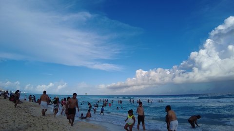 Cancun, Quintana Roo, Mexico - December 18, 2021: Busy beach in Cancun with tourists swimming and watching the waves. Cancun is the most visited tropical beach destination in Mexico. 
