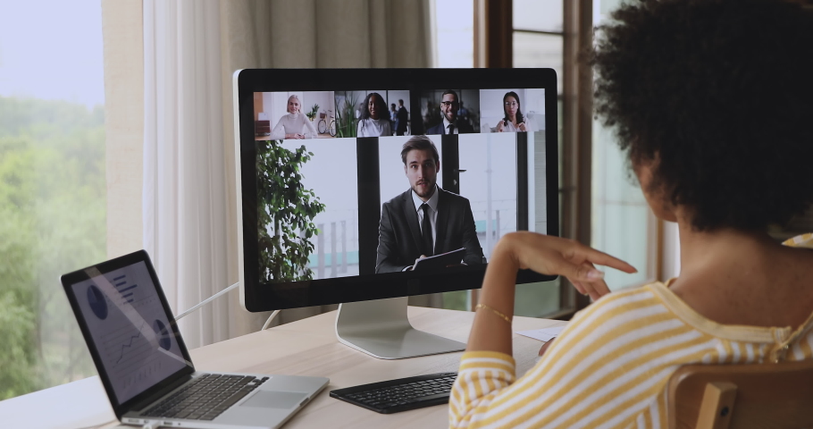 Diverse business partners take part in video call, pc monitor view over shoulder of African businesswoman. Company briefing, group brainstorm, virtual meeting through videoconference, teamwork concept Royalty-Free Stock Footage #1085933969