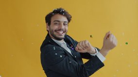 Portrait of Middle Eastern dancer moving while confetti falling down in air during holiday celebration. Man in elegant suit dancing on yellow background. - Powered by Shutterstock - Get 15% off with code: PIKWIZARD15