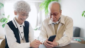 Old aged Asian couple using a smart phone.
