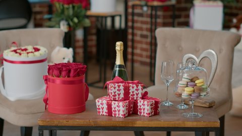 Romantic valentine day luxury setup with gift boxes champagne and macarons on coffee table with elegant roses bouquet. Living room with surprise love theme decoration flowers and teddy bear.