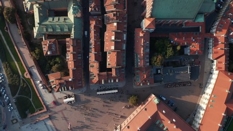 Aerial birds eye overhead top down panning view of red tiled rooftops and squares in historic centre of old town. People walking and sightseeing. Warsaw, Poland