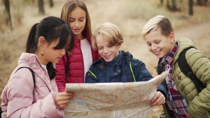 Smiling multinational group of children looking at the map in park