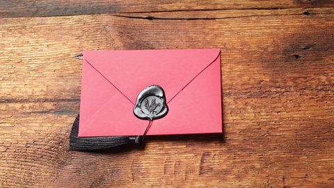 A red envelope sealed with sealing wax is placed on a wooden surface. Love correspondence.