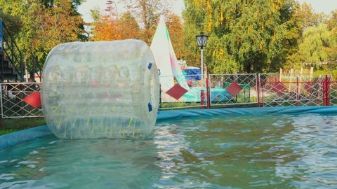 Bryansk, Russia - 09.12.2021: Big plastic bubble on water for children. Zorbing in swimming pool. Favourite children's water activities.