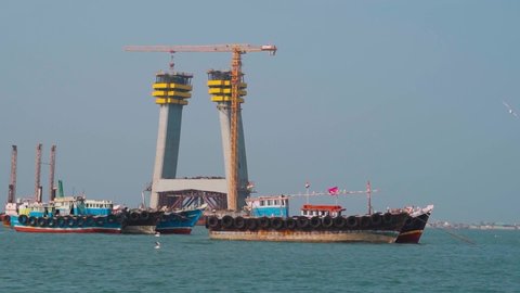 Boats in the sea moving in front of the Signature cable bridge under construction between Okha and Beyt Dwarka at Gujarat, India Stockvideo