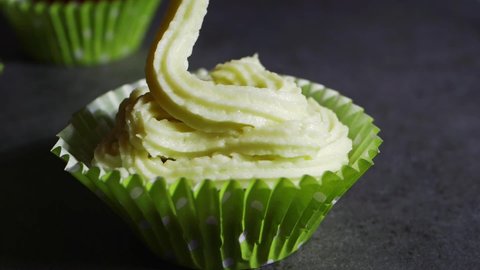 Decorating cupcakes with icing and piping bag close up slow motion shot selective focus