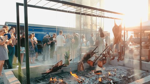 Russia, St. Petersburg, 18 August 2019: Large chunks of pork, beef and pineapple meat are cooked on a huge grill, burning logs on a sheet of iron as coals, the pig's head is baked on an open fire.