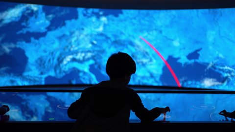 Dubai, United Arab Emirates - January 2022: Expo 2020 Museum of future. LCD video wall liquid crystal monitor display. Technology boy Child touch screen button futuristic artificial intelligence world
