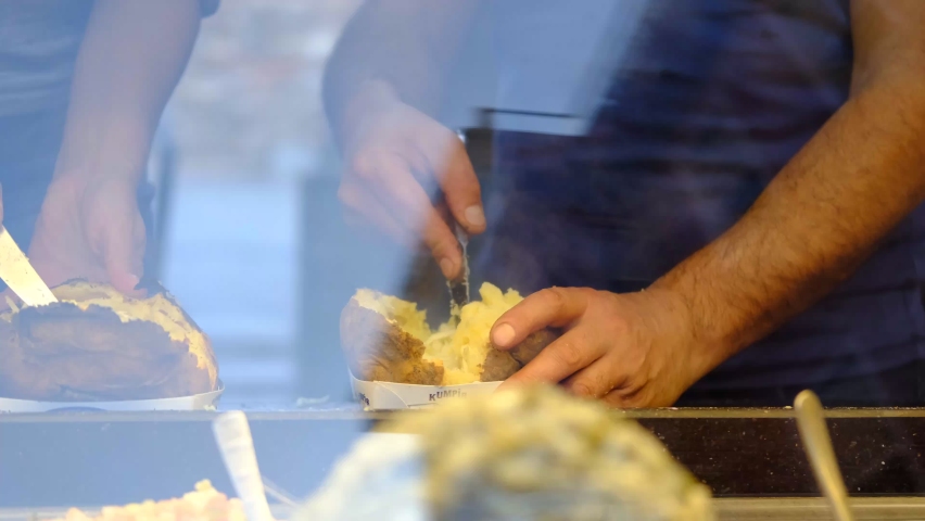 Making kumpir behind the kumpir sales stand, a street flavor served by adding various sauces and appetizers to the baked potato
