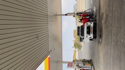 WINDHOEK, NAMIBIA - NOVEMBER, 11, 2021: Vertical video. Car refueling at gas station with fuel or diesel. White Toyota Hilux SUV at Shell. Road travel in South Africa. Summer vacations.
