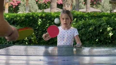 Blonde girl success play table tennis, known as ping-pong. Female child player hit lightweight ping-pong ball, back and forth across hard table divided by tennis net use small rackets. Real people