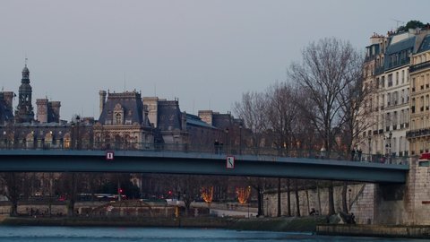 Tourists crossing river seine on bridge while city lights light up Paris time lapse 4k 30p
