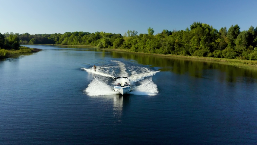 Drone video of a wakeboarder behind a boat on a lake
