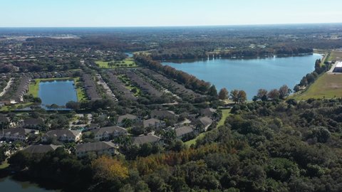 Modern estate of single-family houses in suburbs of Sarasota, Florida. Detached houses with green surroundings and regulated lakes. Higher aerial view