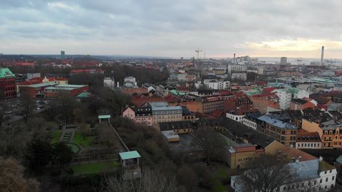 Ascending aerial view over cityscape of Helsingborg with flying birds during sunset at horizon,Sweden