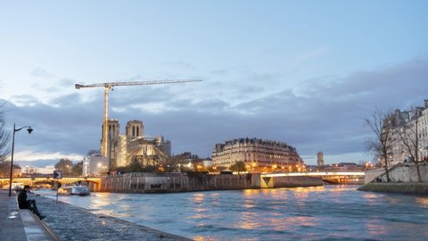 Notre dame being worked on at night time lapse with river seine and tourists sightseeing 4k 30p