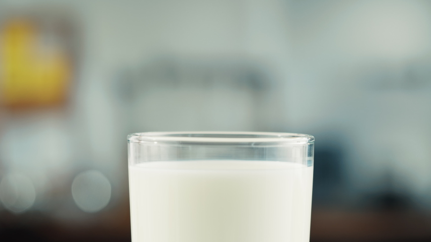 Eating cookie with milk in glass cup close-up. Glass with yogurt, dairy products concept. Drinking fresh lactose-free milk in morning. Royalty-Free Stock Footage #1085981120