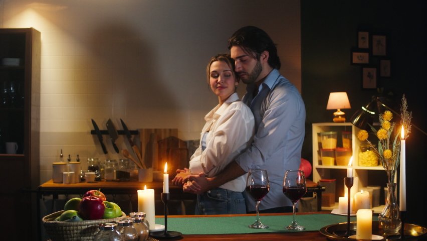 Man and woman dancing in cozy kitchen, romantic date dinner. Young husband and wife drinking red wine in evening. Loving couple, happy family relationships. Celebrating Valentine's Day together.  Royalty-Free Stock Footage #1085981249