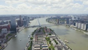 Inscription on video. Rotterdam, Netherlands. Norderayland Island ( North Island ) and Erasmus Bridge ( Erasmusbrug ) over the Nieuwe Maas River. Arises from blue water, Aerial View, Point of interes