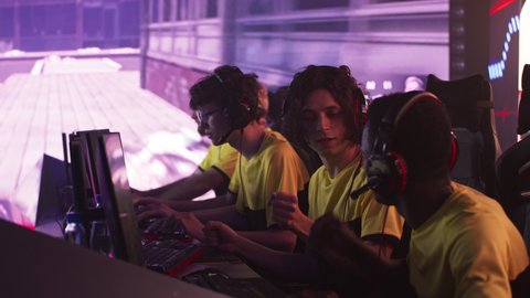 Team of diverse male gamers esportsman putting on headphones and bumping fists at start of professional gaming match