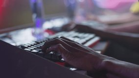 Unrecognizable African American esports gamer using keyboard to play shooter on computer battle during professional gaming tournament