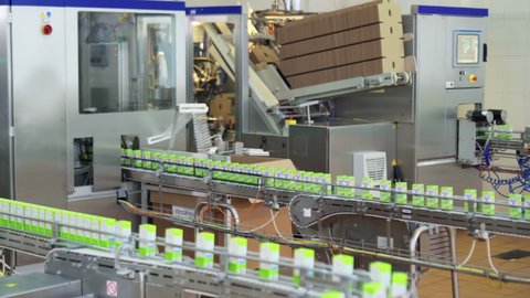 Multiple Green Cartons Of Milk On Conveyor Line In Industrial Facility. Conveyor Line At Factory For Dairy Products Manufacturing. Packaging Equipment At Plant. Conveyor Line. Automated Processes.