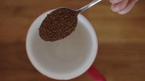 UHD 4k Slow Motion of Instant Coffee Pieces Falling From Spoon in Red Cup. Footage B roll scene of Coffee Powder Falling From Spoon. Fresh Morning Hot Coffee Close Up.
