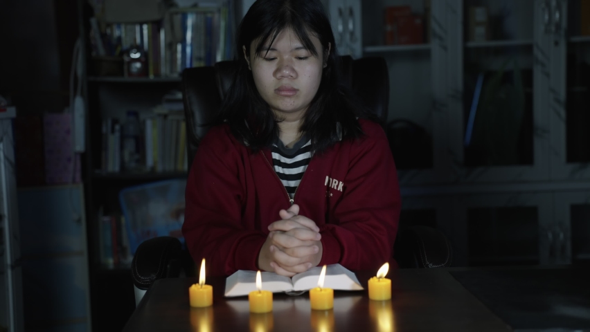 UHD 4k Slow motion B roll of young christian while praying and worship for Jesus. christian people praying while hands worship over a Bible. learning religion. Self worship of god. Low light shoot.