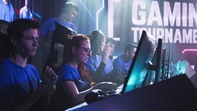 Happy esportsman gamer woman talking with male teammates then putting on headphones and starting to play video game during esports championship