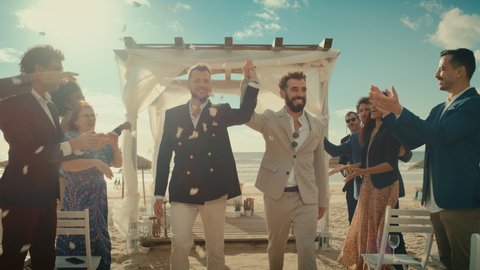 Handsome Gay Couple Walking Up the Aisle at Outdoors Wedding Ceremony Venue Near Ocean. Two Happy Men in Love Share Their Big Day with Diverse Multiethnic Friends. Cute LGBTQ Relationship Goals.