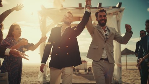 Handsome Gay Couple Walking Up the Aisle at Outdoors Wedding Ceremony Venue Near Sea. Two Happy Men in Love Share Their Big Day with Diverse Multiethnic Friends. Authentic LGBTQ Relationship Goals.