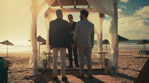 Handsome Gay Couple Walking Down the Aisle at Outdoors Wedding Ceremony Venue Near the Sea. Two Happy Men in Love Share Their Big Day with Diverse Multiethnic Friends. Cute LGBTQ Relationship Goals.