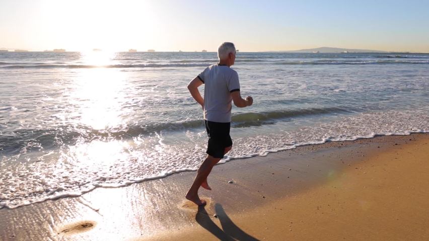 64 year old man getting his exercise at the beach at sunset. Slow Motion.