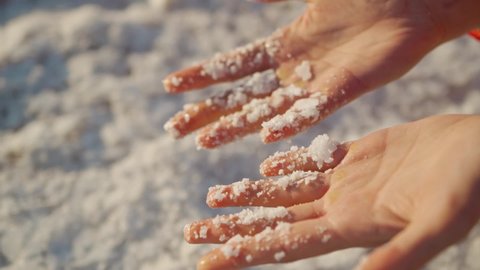 Top view slow motion closeup woman hands holding crystallized salt natural mineral formation at Dead Sea coastline with highlight sunlight