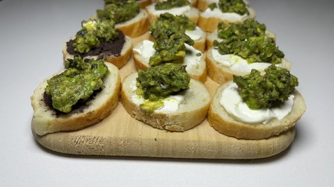 Avocado on top spread on bread with cream cheese and black olive paste amazing snack food wellness presentation on wooden board ready to serve 4K video footage buying now.