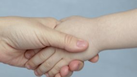 adult hand and kid's hand close up video. hand shake on grey background. communication concept, agreement in family.