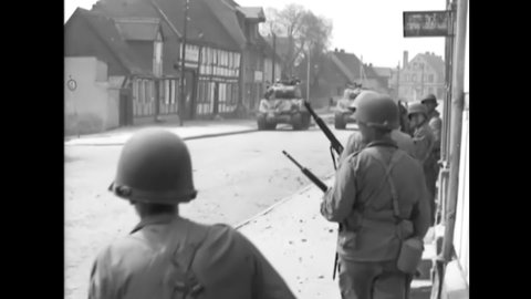CIRCA 1945 - American soldiers and tanks move slowly up a street in Tangermunde, Germany. Medics take a wounded man out of a tank.