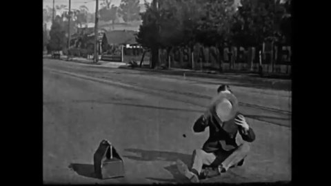CIRCA 1921 - In this silent film, a man chases down his dog when it runs away in his bag, and he interrupts a holdup.