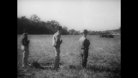 CIRCA 1936 - J. Edgar Hoover oversees firing practice in a field, where federal agents shoot at a car with a variety of guns in a simulation.