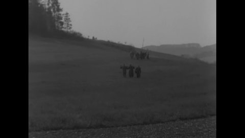 CIRCA 1945 - German soldiers carry white flags across a field to American soldiers, and a German tank burns.