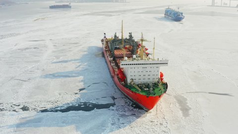 A drone view of the nuclear-powered lighter carrier Sevmorput in the road at anchor in the ice. The concept of cargo transportation along the Northern Sea Route - JAN 16, 2022 VLADIVOSTOK, RUSSIA