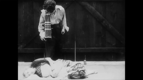 CIRCA 1915 - In this silent comedy, a peasant (Charlie Chaplin) revives his unconscious lover.