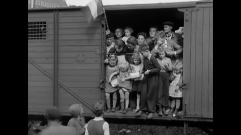CIRCA 1945 - Refugee families wave from freight cars set to depart Camp Schonau.