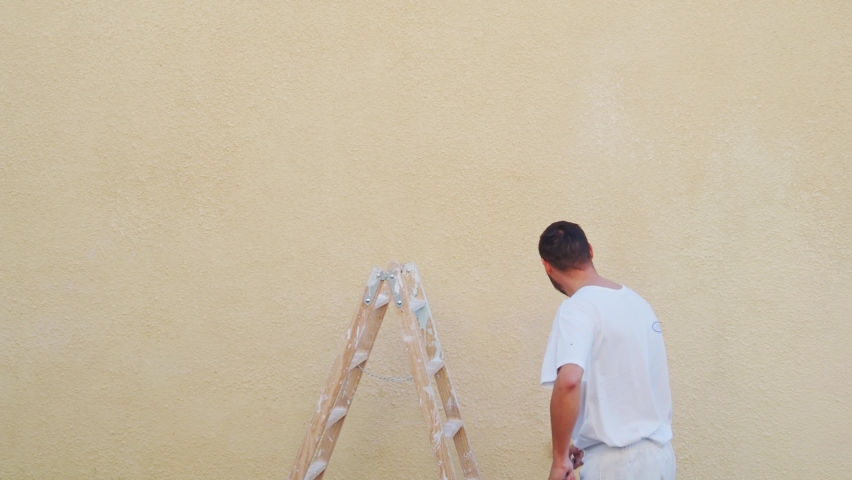 Painter man painting a wall with a roller. Home renovations | Shutterstock HD Video #1086023168