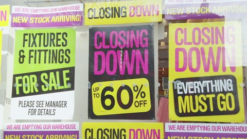 Closing down sale signs in a shop window, slow pan